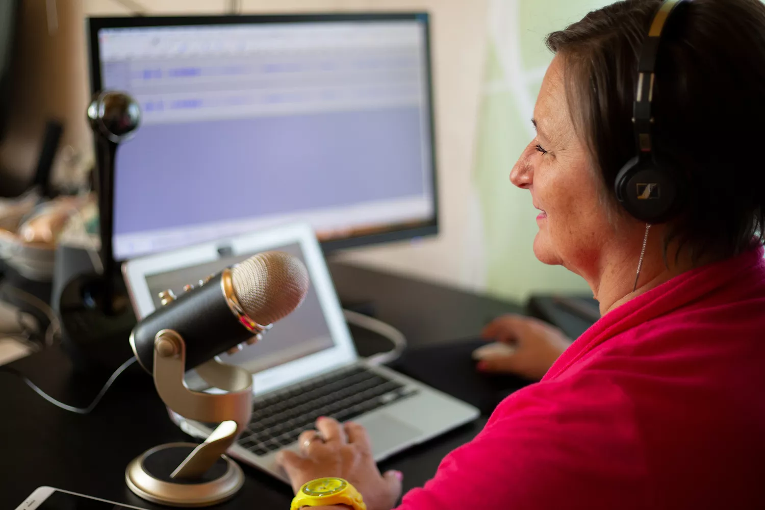 Heike bei einer Podcastaufnahme mit Mikrofon, Laptop, Monitor