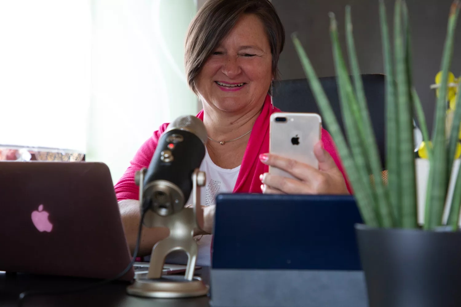 Mrs. Mobile (Heike Stiegler) am Schreibtisch mit Handy, Mikrofon, Tablet und Laptop